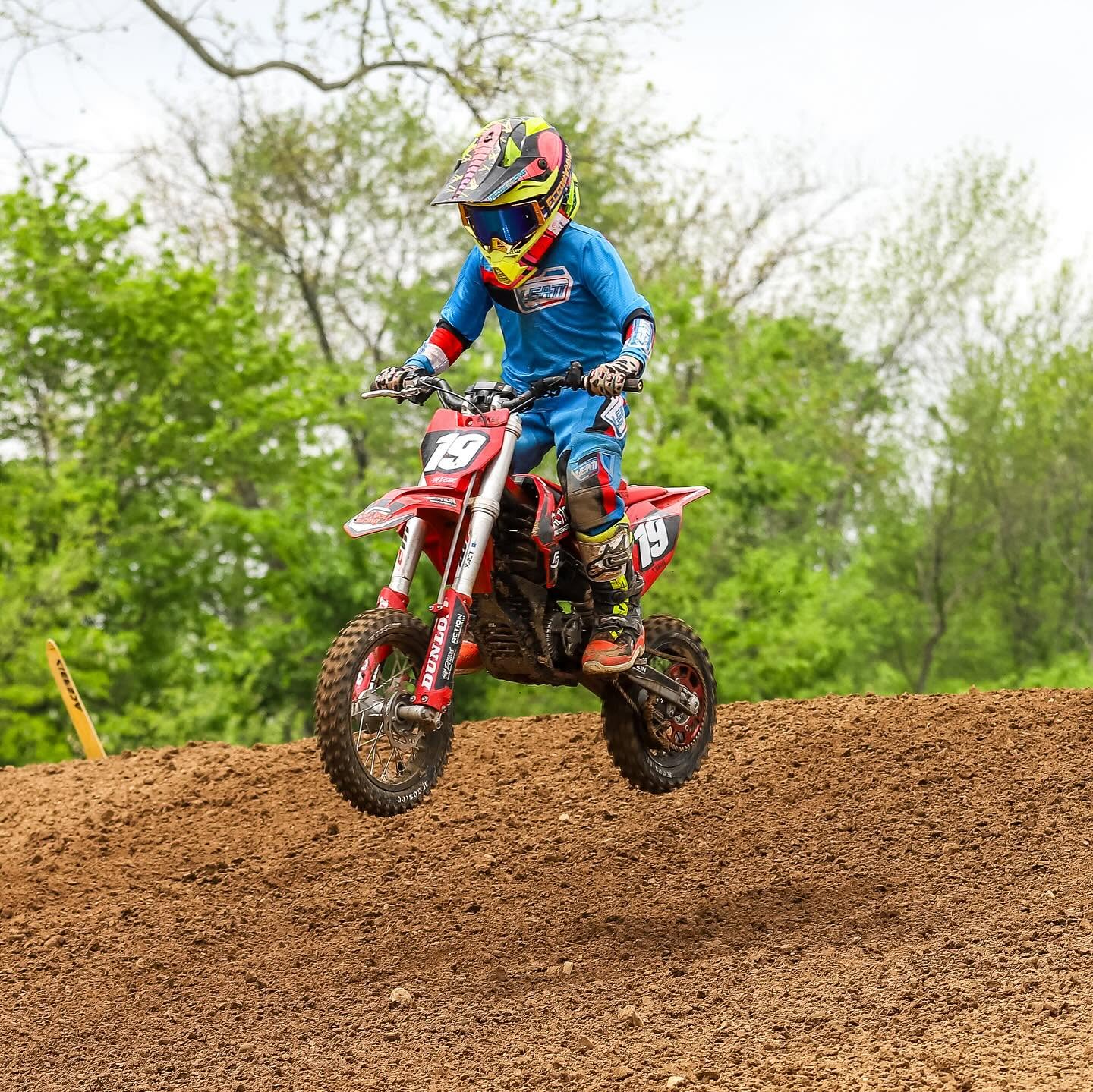 Youth motocross rider cresting a dirt jump