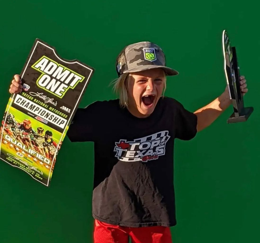 Young motocross rider celebrating with a championship plaque